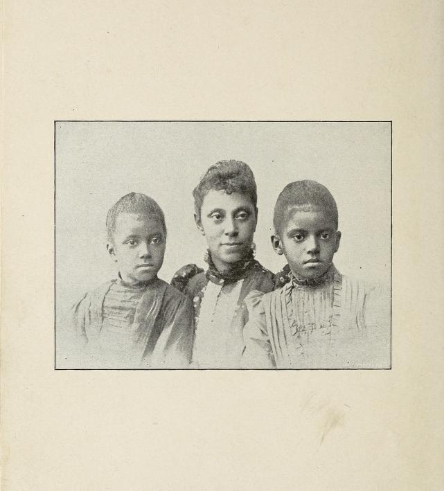 N. F. Mossell is sitting between her two daughters. All are facing front.