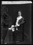 Full body photo of A.J. Cooper seated, looking front, and holding a book.