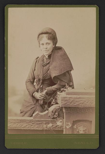 Sepia photograph of Hallie Quinn Brown standing, looking front.