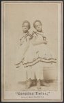 Full body photo of the sisters standing, both looking front.