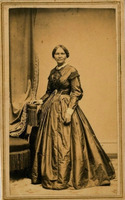 Full body photo of Elizabeth Keckley standing and looking front, her left hand on a chair.