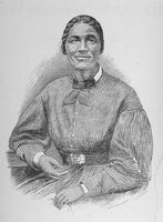Bethany Veney seated and holding an item in her left hand.