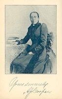 3/4 photo of A.J. Cooper seated and facing front, with one arm resting on a table with books. 