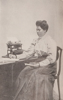 3/4 body photo of L. A. J. Moorer seated, holding a pen in one hand and a book in the other.