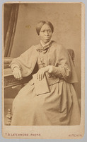 3/4 body photo of Amanda Smith sitting and looking right. She is holding a book.