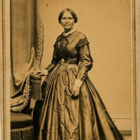 Full body photo of Elizabeth Keckley standing and looking front, her left hand on a chair.