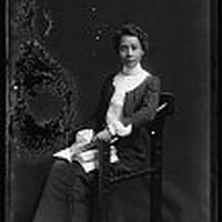 Full body photo of A.J. Cooper seated, looking front, and holding a book.