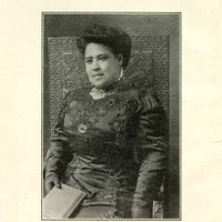 3/4 body photo of Leila Amos Pendleton seated and facing front. She is holding a book.