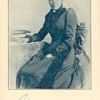 3/4 photo of A.J. Cooper seated and facing front, with one arm resting on a table with books. 