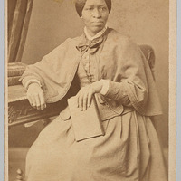 3/4 body photo of Amanda Smith sitting and looking right. She is holding a book.