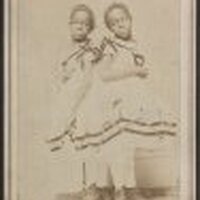 Full body photo of the sisters standing, both looking front.