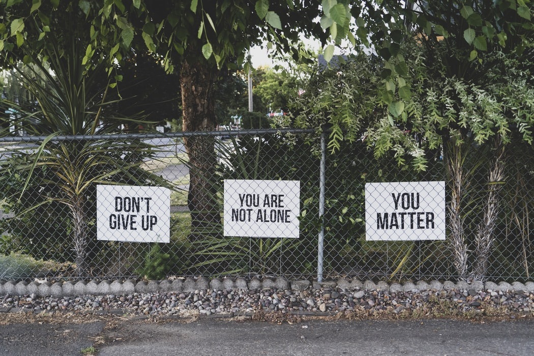 Signs on Fence that say: Don’t Give Up; You Are Not Alone; You Matter